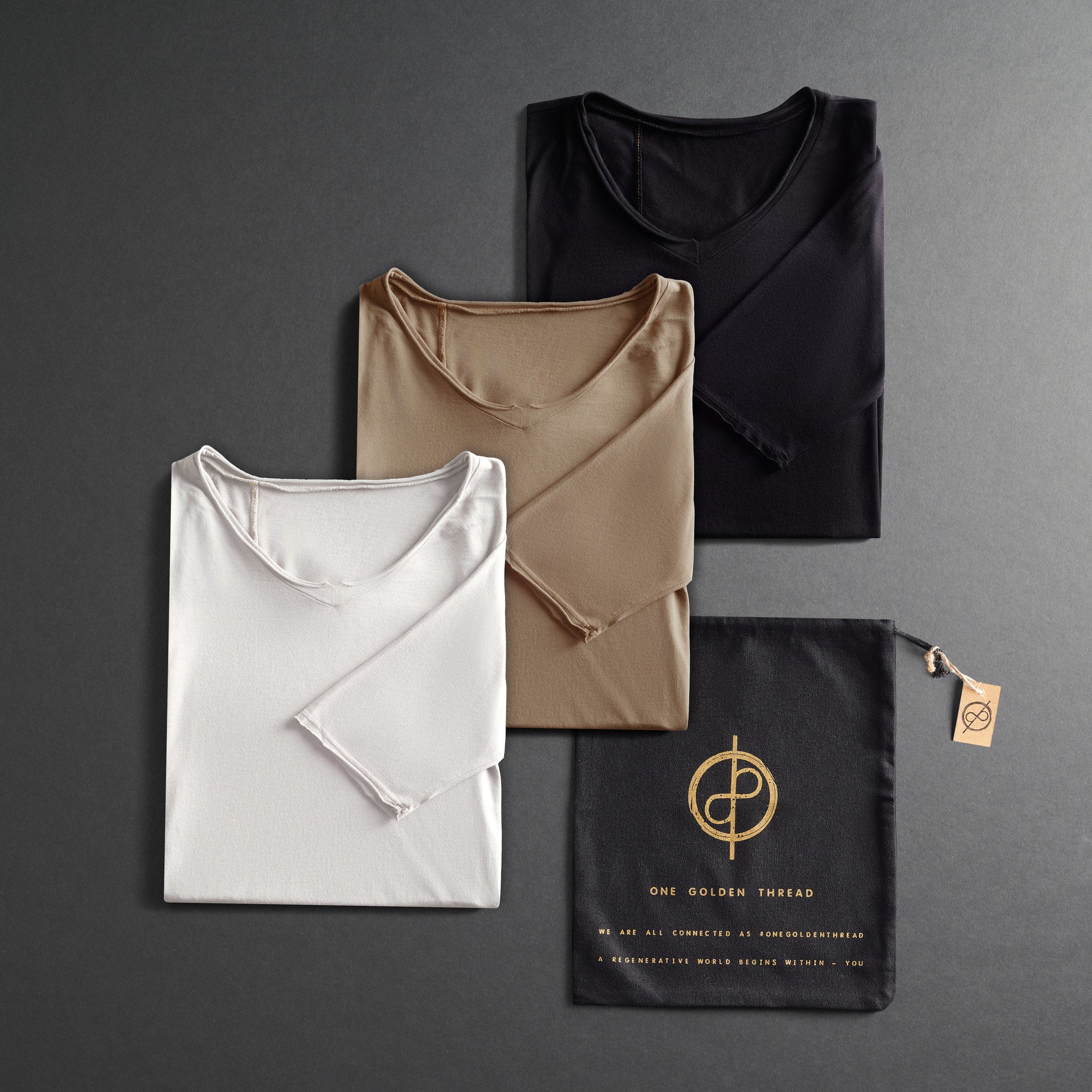 Three black T-shirts hanging on wooden hangers against a white background.