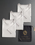 three folded shirts in white on a dark gray background