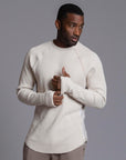 A man modeling a One Golden Thread Waffle Long Sleeve Raglan shirt in white stone