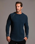 A man modeling a One Golden Thread Waffle Long Sleeve Raglan shirt in blue mineral