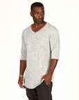 A man modeling in a grey mineral sweater v neck shirt