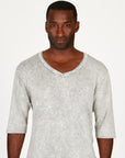 A man modeling in a grey mineral sweater v neck shirt