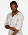 A man modeling in a grey mineral sweater v neck shirt