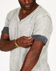 A man modeling in a grey mineral sweater v neck shirt with the sleeves rolled up