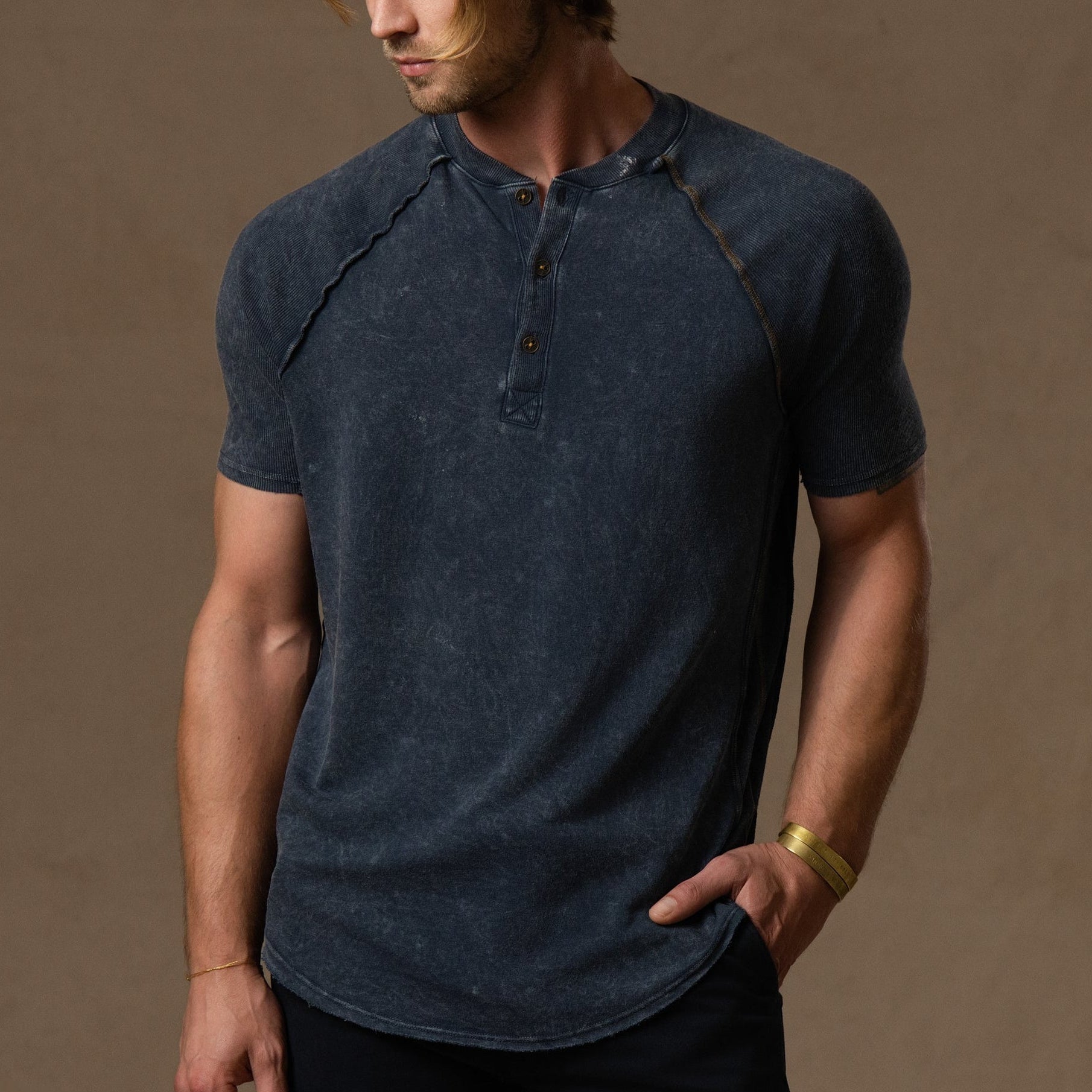 Man wearing a light grey short-sleeve henley shirt with button details.