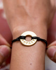 A person gifting a Customized MyIntent Gold Plated Black Twist Bracelet with the word "Impact"