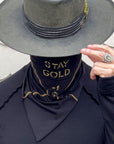 A man wearing the One Golden Thread Versawrap as a face covering with the message "Stay Gold" in Black color
