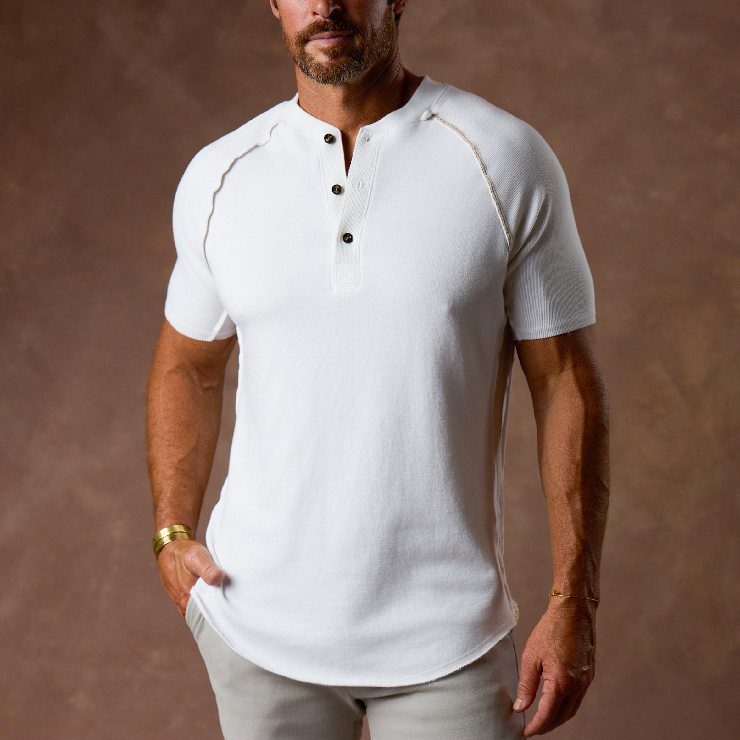Man wearing a light grey short-sleeve henley shirt with button details.