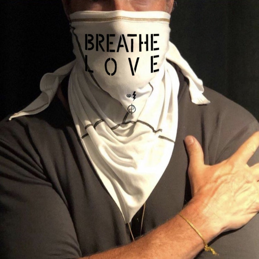 A man wearing the Artist Collab: Gem & Bolt x One Golden Thread Versawrap as a face covering with the message "Breathe Love" in white color