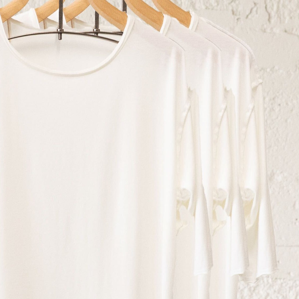White crew neck three pack on wooden clothing racks