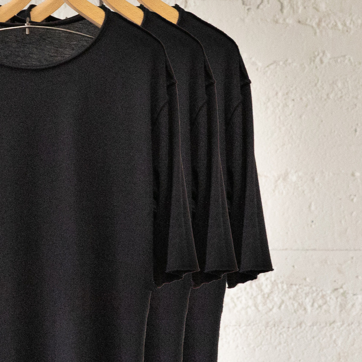 Black crew neck three pack on wooden clothing racks