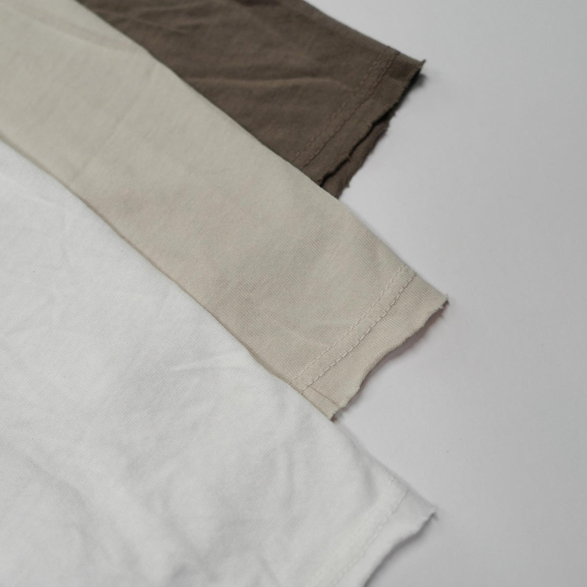 Flat lay of three crew neck shirts in different colors