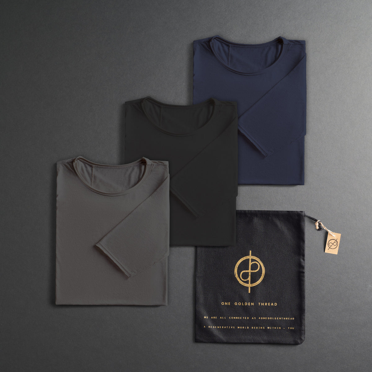 three folded shirts in different colors on a dark gray background