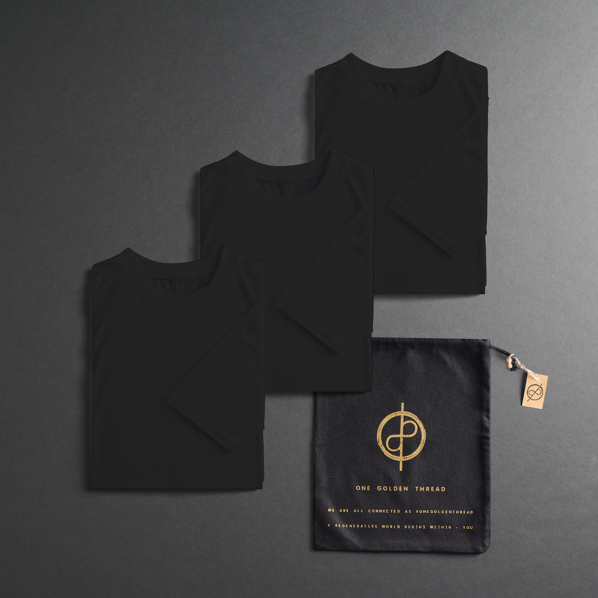 three folded shirts in black on a dark gray background