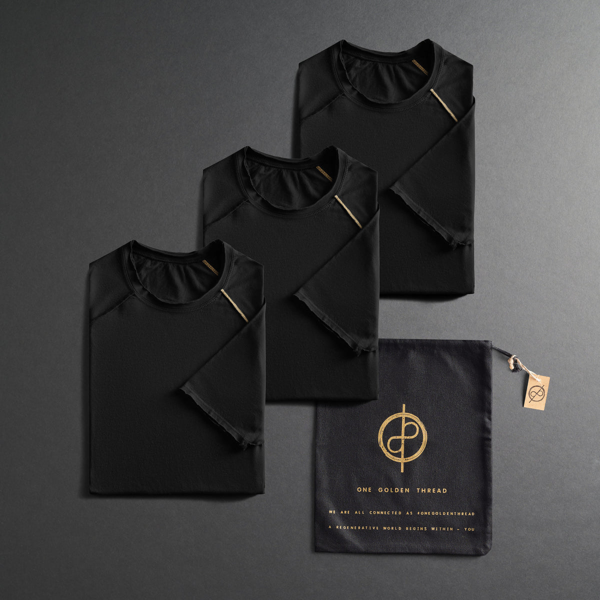 three folded black shirts on a dark gray background