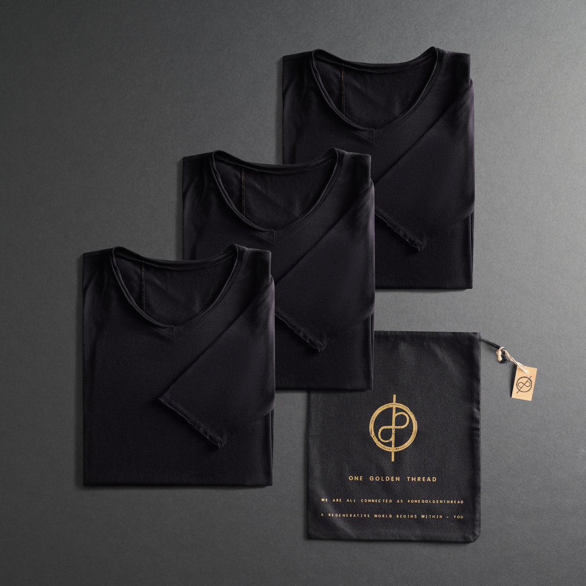 three folded shirts in black on a dark gray background