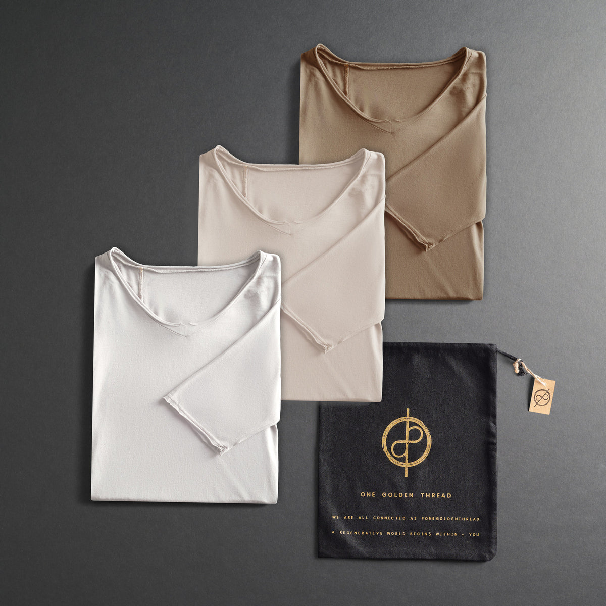 three folded shirts in different colors on a dark gray background
