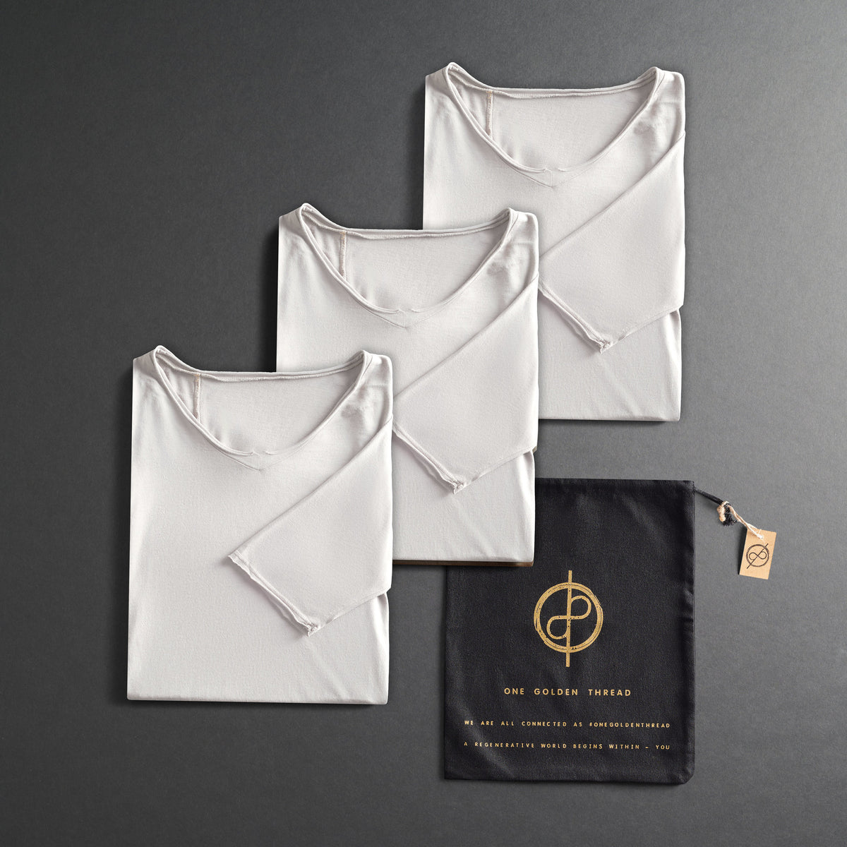 three folded shirts in white on a dark gray background