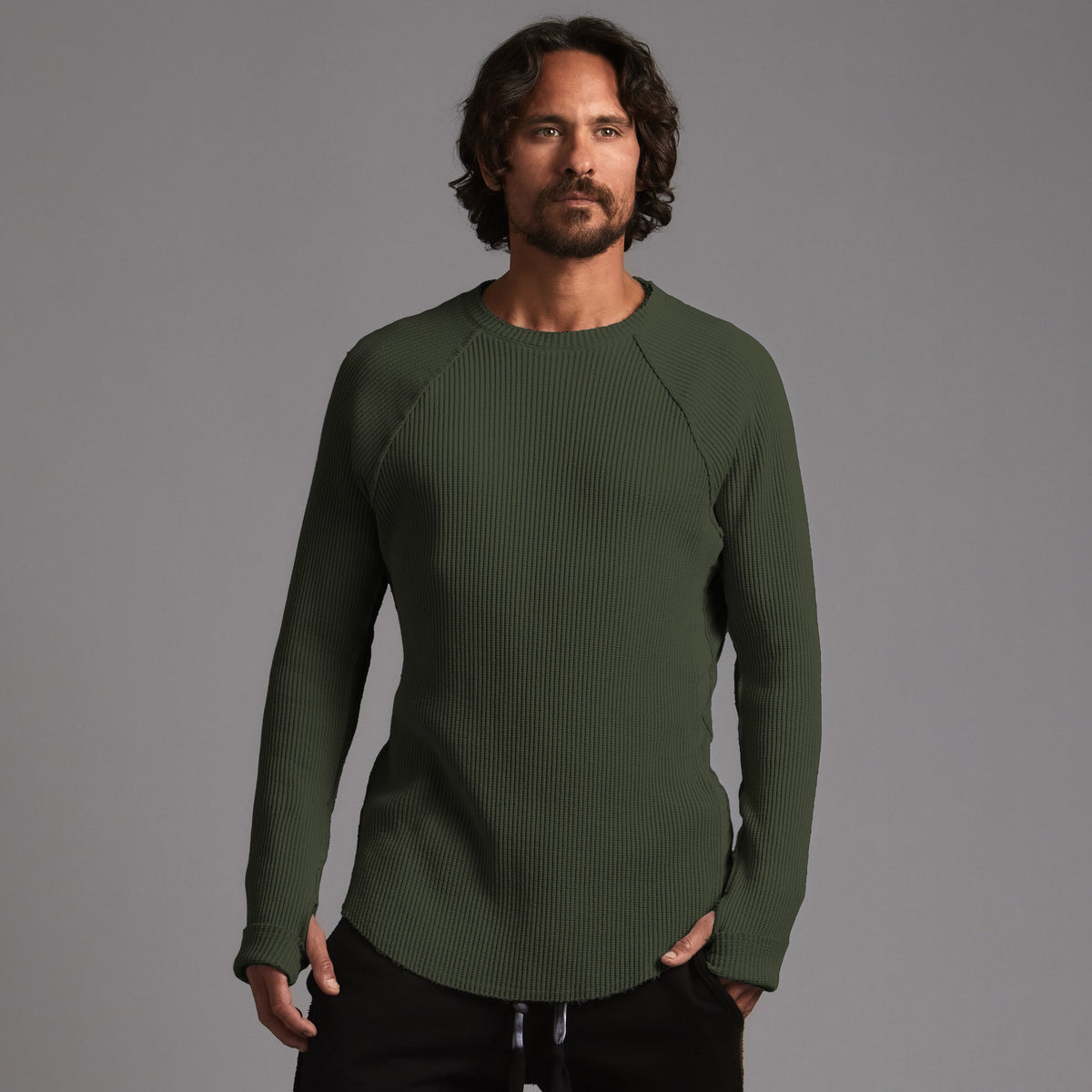 A man modeling a One Golden Thread Waffle Long Sleeve Raglan shirt in urban forest green