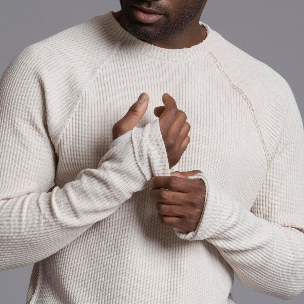 A man modeling a One Golden Thread Waffle Long Sleeve Raglan shirt in white stone