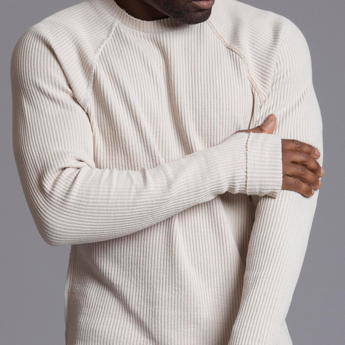 A man modeling a One Golden Thread Waffle Long Sleeve Raglan shirt in white stone