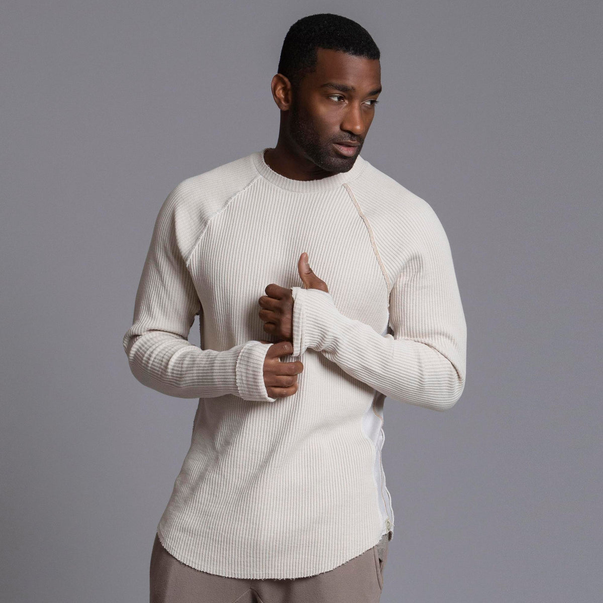 A man modeling a One Golden Thread Waffle Long Sleeve Raglan shirt in white stone