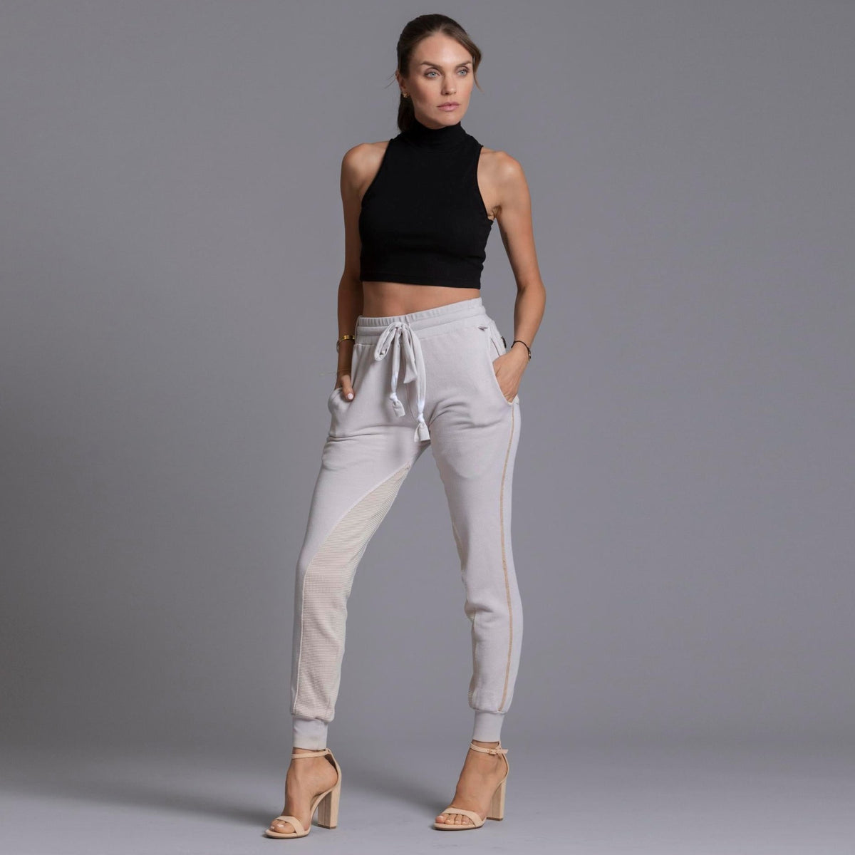 A woman modeling the One Golden Thread Jogga Pants in White Stone 