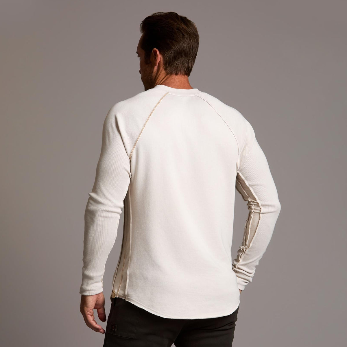 Man modeling a beige long-sleeve shirt against a gray background