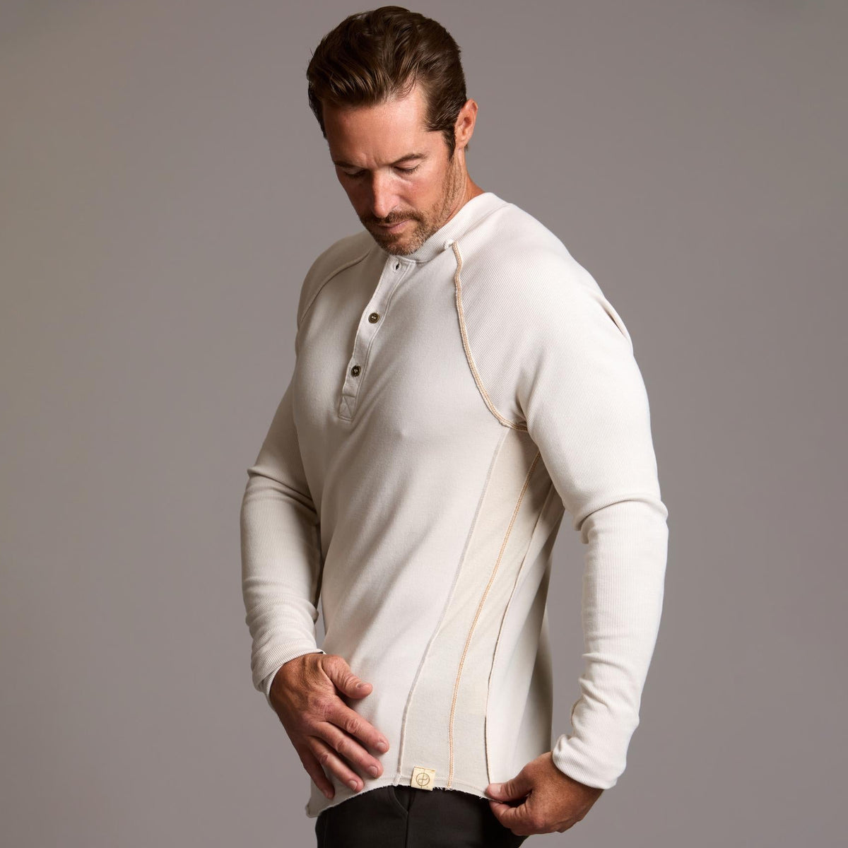 Man modeling a beige long-sleeve shirt against a gray background