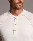 Man modeling a beige long-sleeve shirt against a gray background