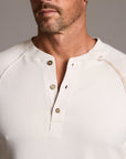 Man modeling a beige long-sleeve shirt against a gray background