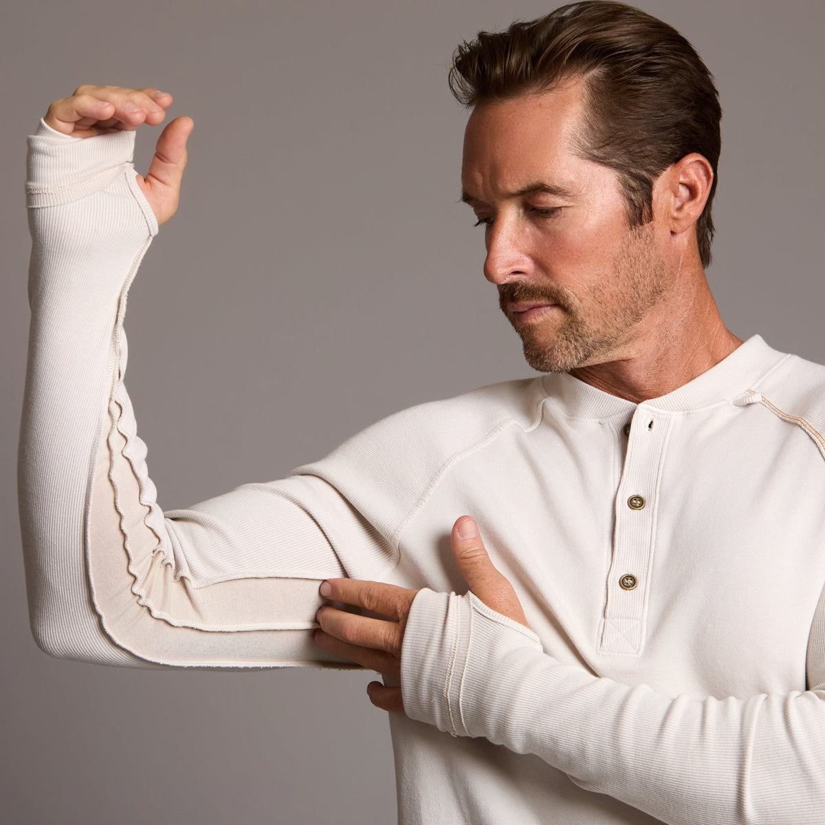 Man modeling a beige long-sleeve shirt against a gray background