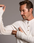 Man modeling a beige long-sleeve shirt against a gray background