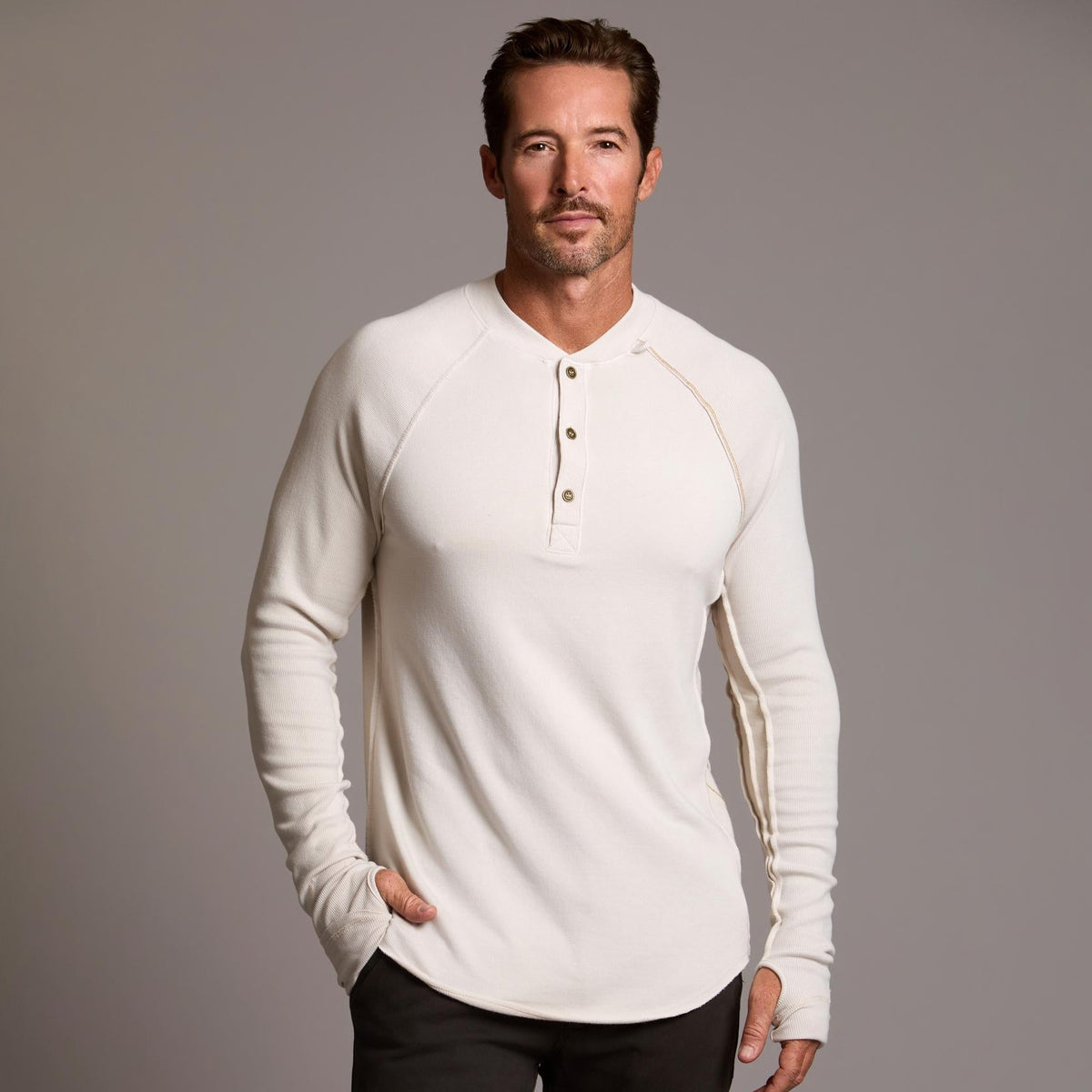 Man modeling a beige long-sleeve shirt against a gray background