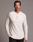 Man modeling a beige long-sleeve shirt against a gray background