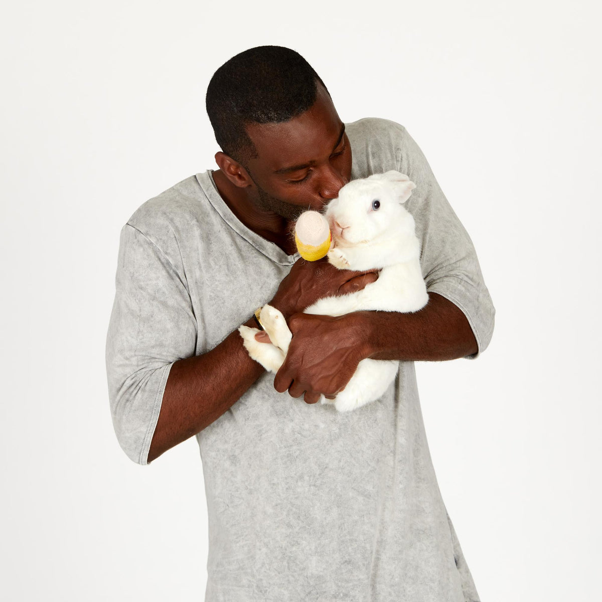 A man wearing the One Golden Thread Fleece Sweater v neck shirt in   grey mineral color while holding a bunny