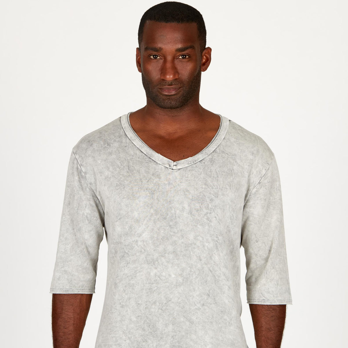 A man modeling in a grey mineral sweater v neck shirt