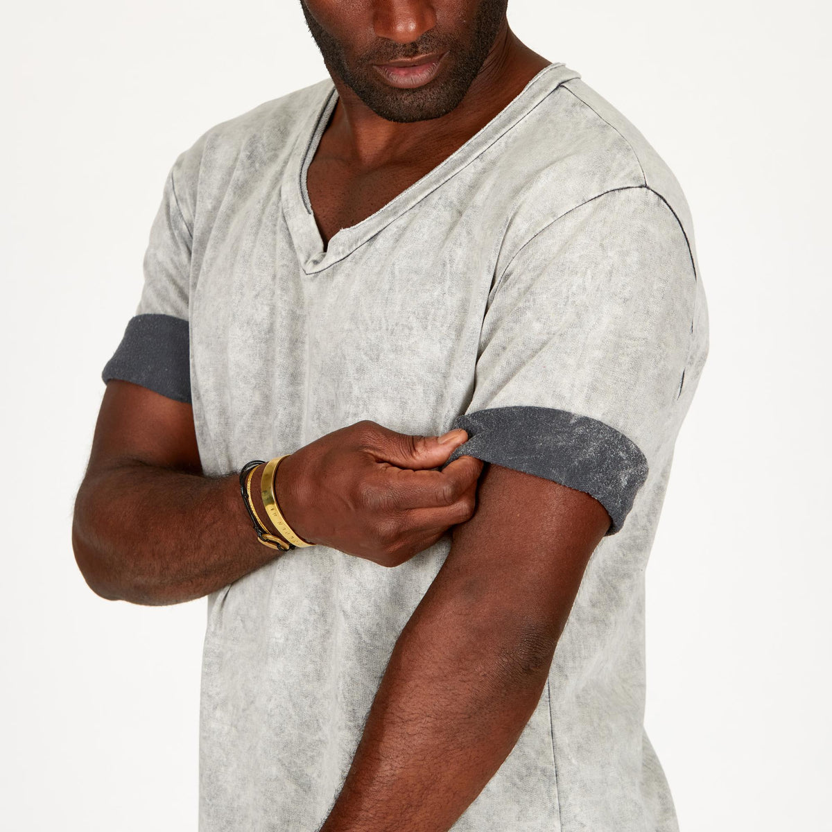 A man modeling in a grey mineral sweater v neck shirt with the sleeves rolled up