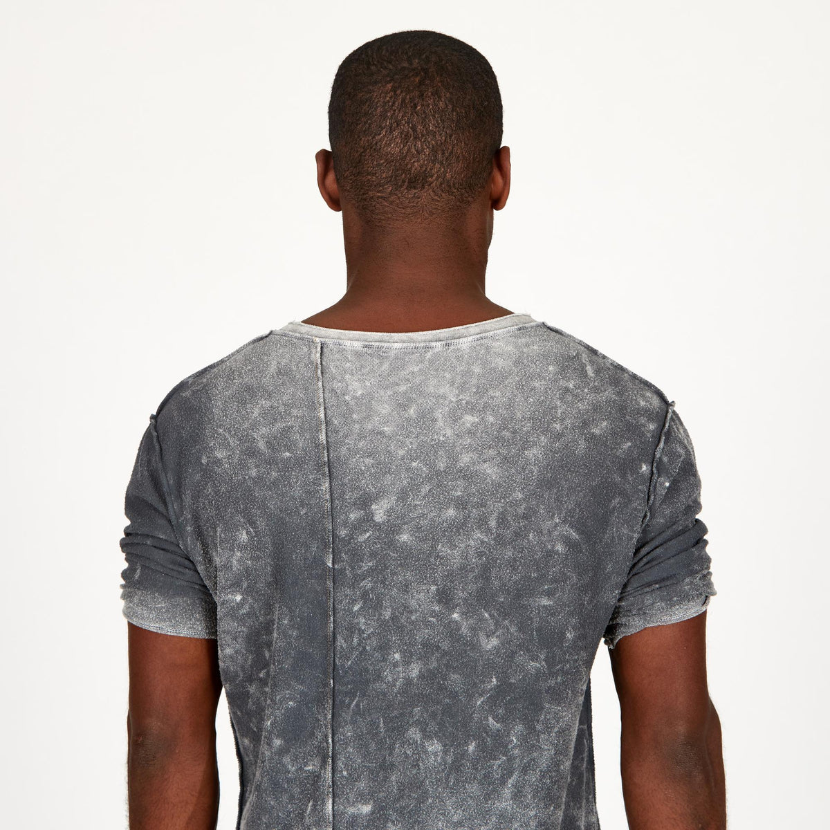 A man modeling in a grey mineral sweater v neck shirt