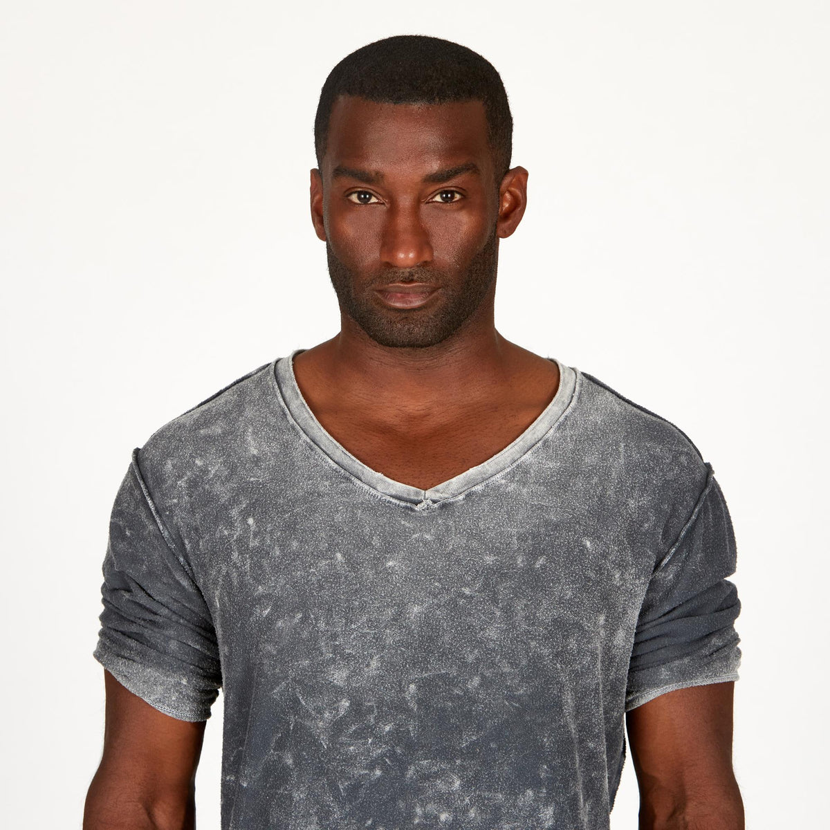 A man modeling in a grey mineral sweater v neck shirt