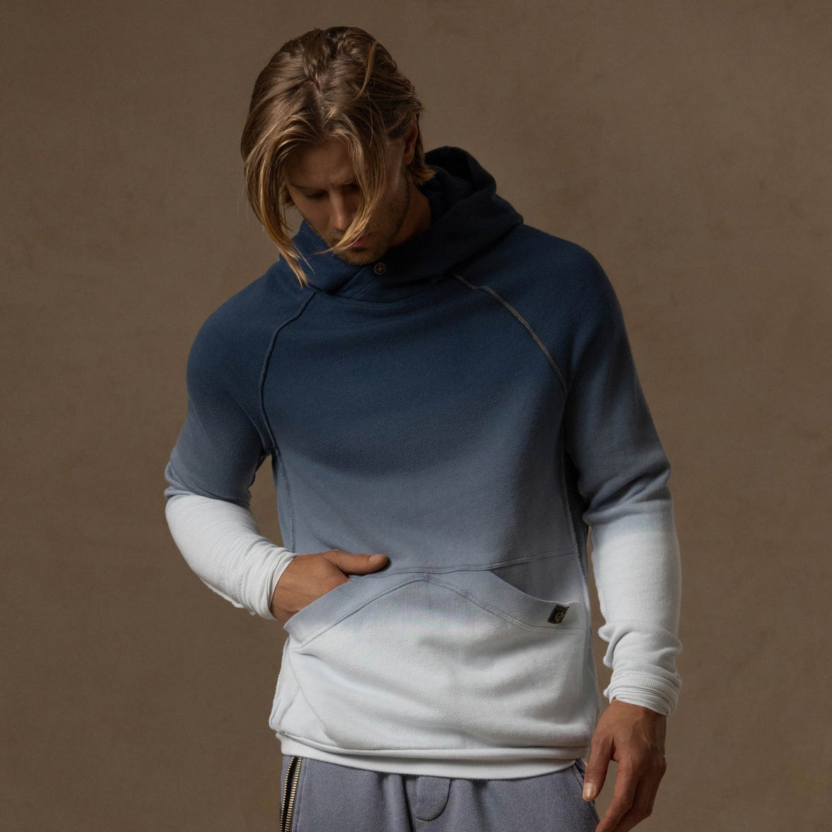 a male modeling the pullover plush hoodie in a grey gradient