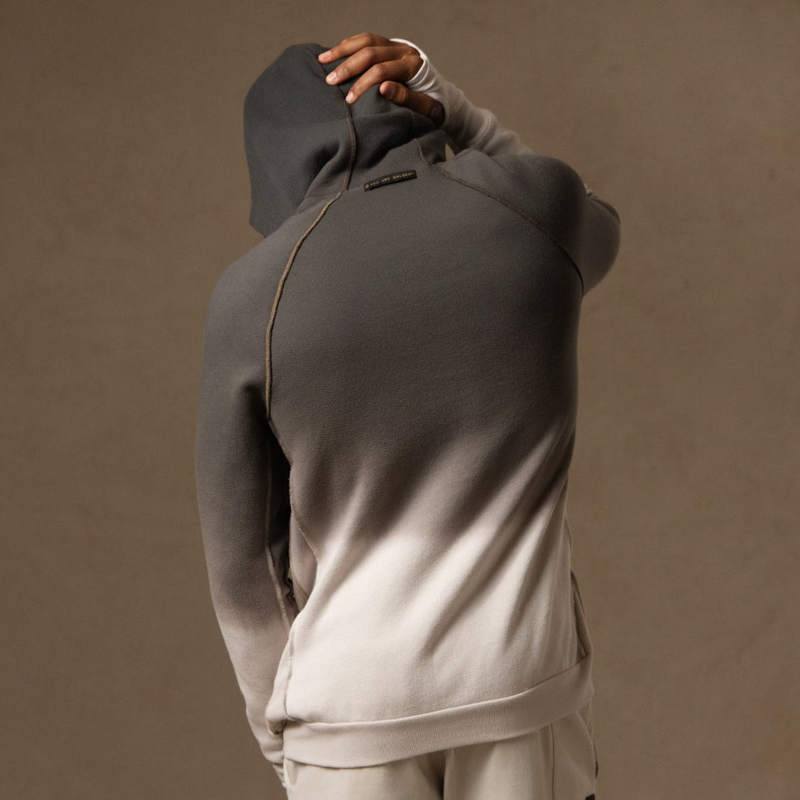 a male modeling the pullover plush hoodie in a grey gradient