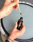 A man with the One Golden Thread "7th Sensuous: All Over Essential Oil" fragrance oil dropper