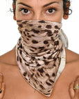 A woman wearing the One Golden Thread Versawrap as a face covering in the "Animal of Life" color design