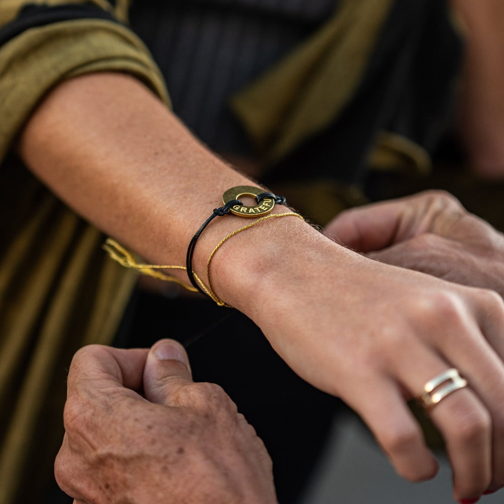 A person gifting a Customized MyIntent Black Twist Bracelet with the word "Grateful"