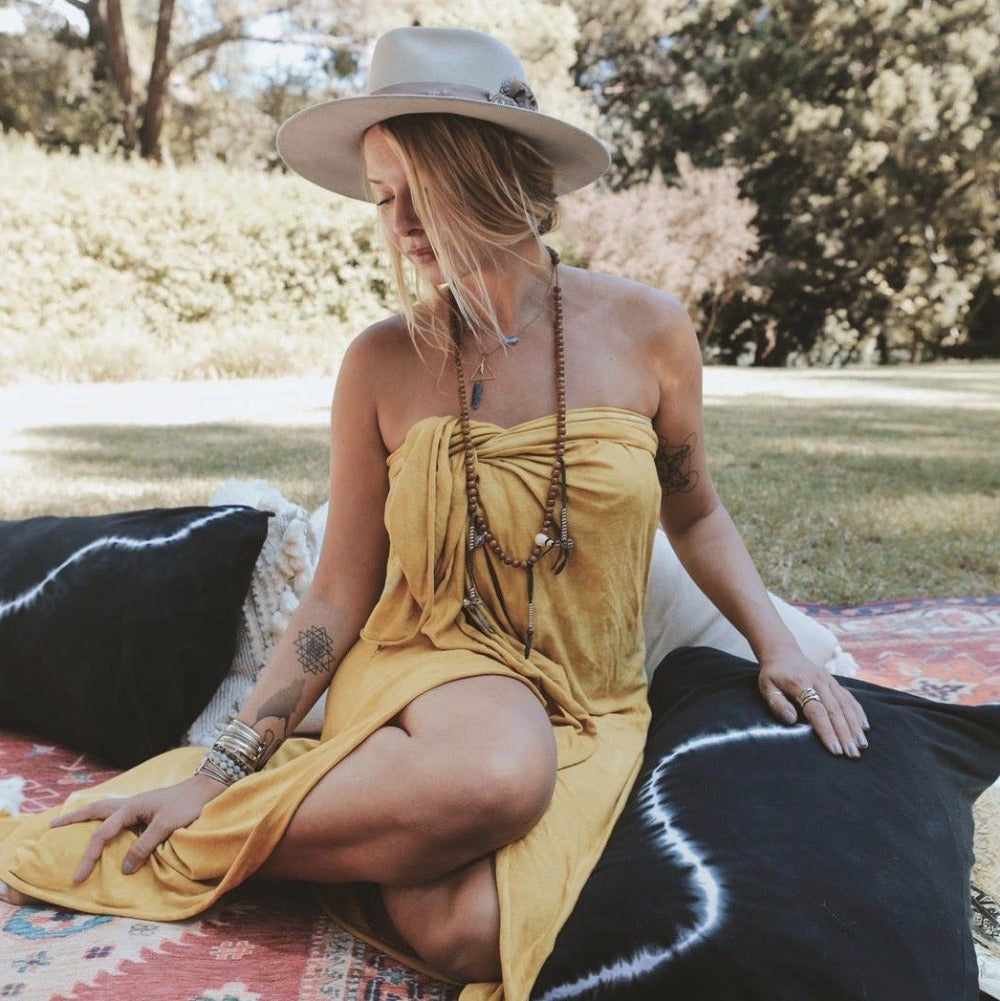 A woman sitting with the One Golden Thread Pillow Face Set in Black Onyx Bolt color