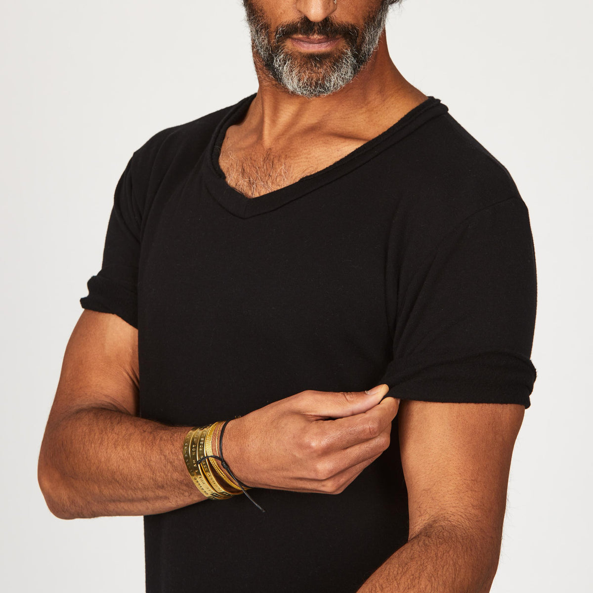 A man modeling in a black sweater v neck shirt with the sleeves rolled up