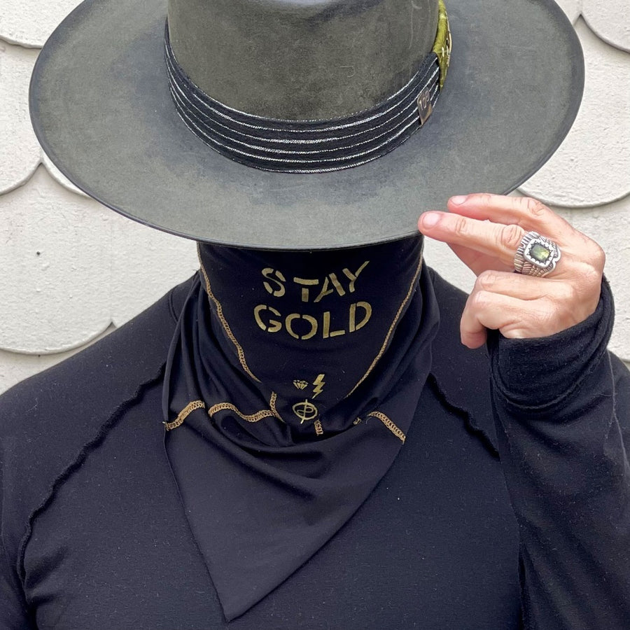 A man wearing the One Golden Thread Versawrap as a face covering with the message "Stay Gold" in Black color