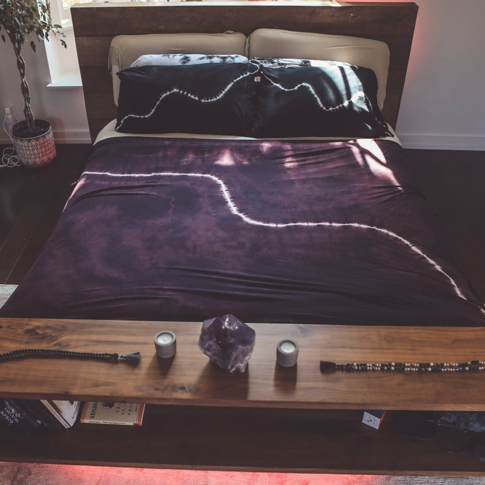 A bed with the One Golden Thread Pillow Face Set in the Black Onyx Bolt and Calico Cloud colors
