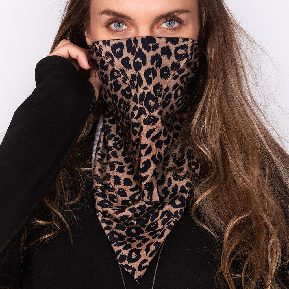 A woman wearing the One Golden Thread Versawrap as a face covering in the "Animal of Golden" color design